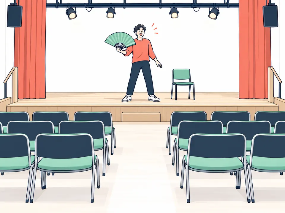 客席のうしろから見た舞台。扇子を持って立つ人と、並んだいす